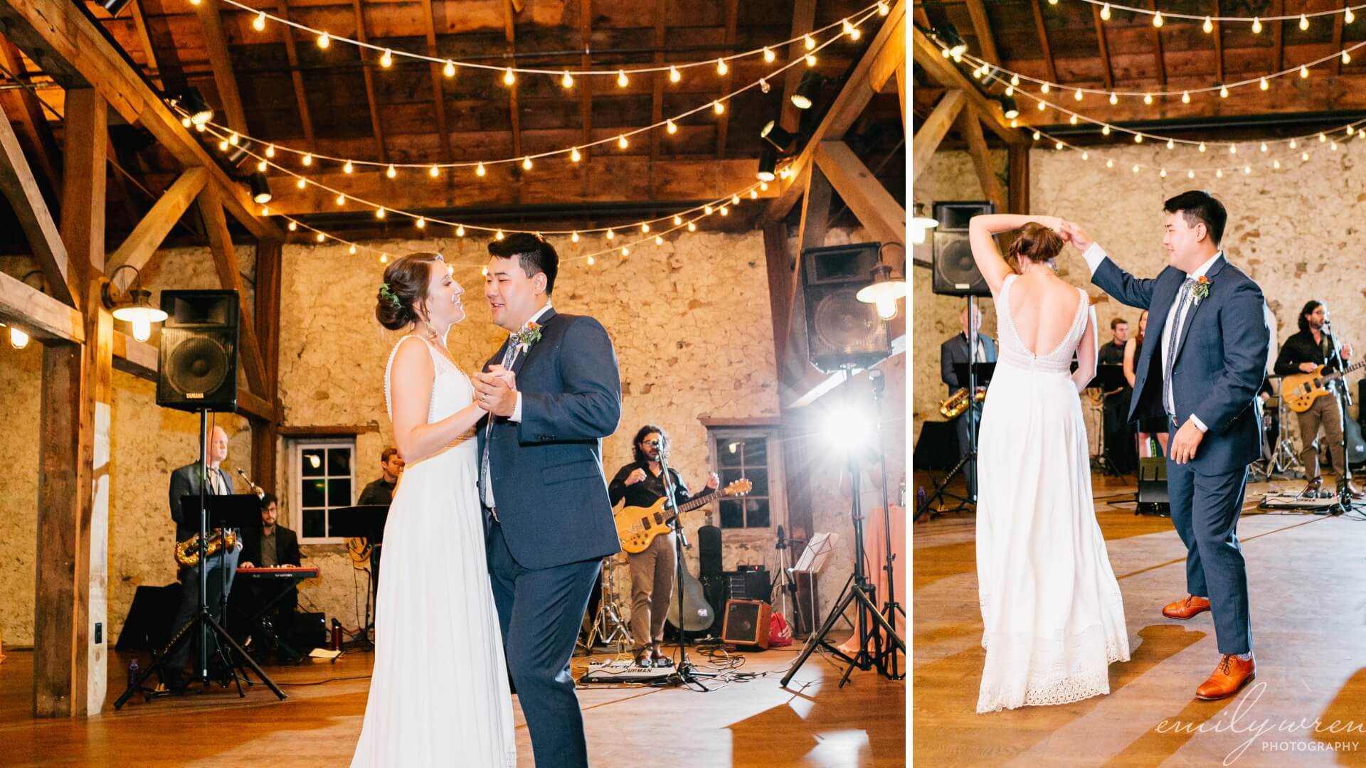 A couple dances in a warmly lit barn during a wedding reception. A band plays in the background under string lights.