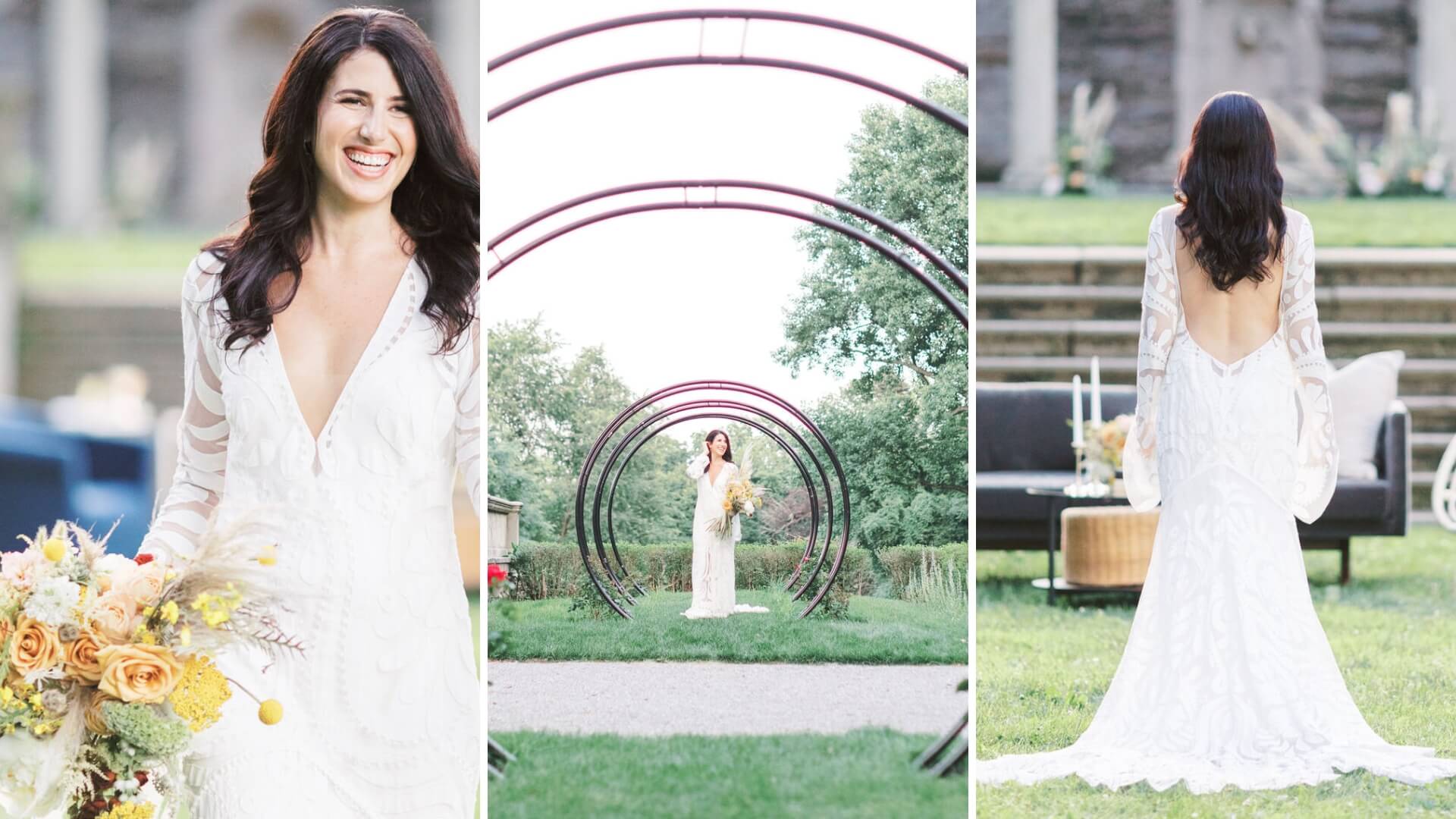 A woman in a white wedding dress holds a bouquet, smiles, and stands in a garden setting. The dress has a deep neckline and open back. She is framed by three circular metal arches.